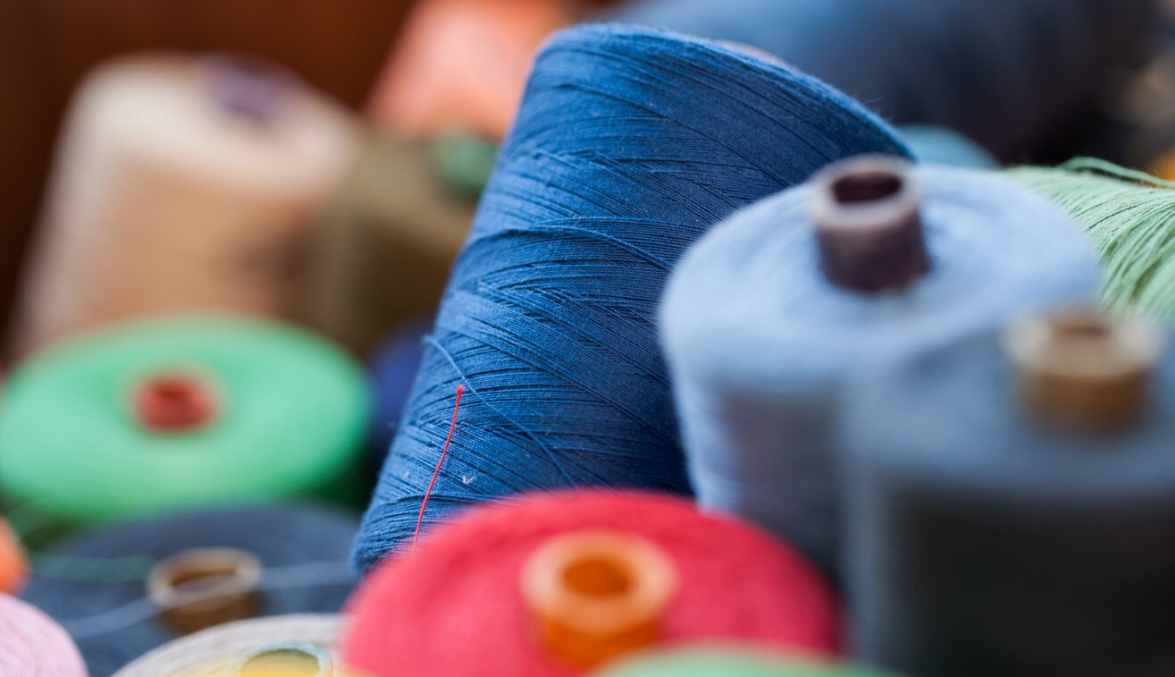 Как выбрать нитки. Швейный цех. Нитки контрастные и в цвет ткани.. Нить контрастного цвета. Текстиль фон.